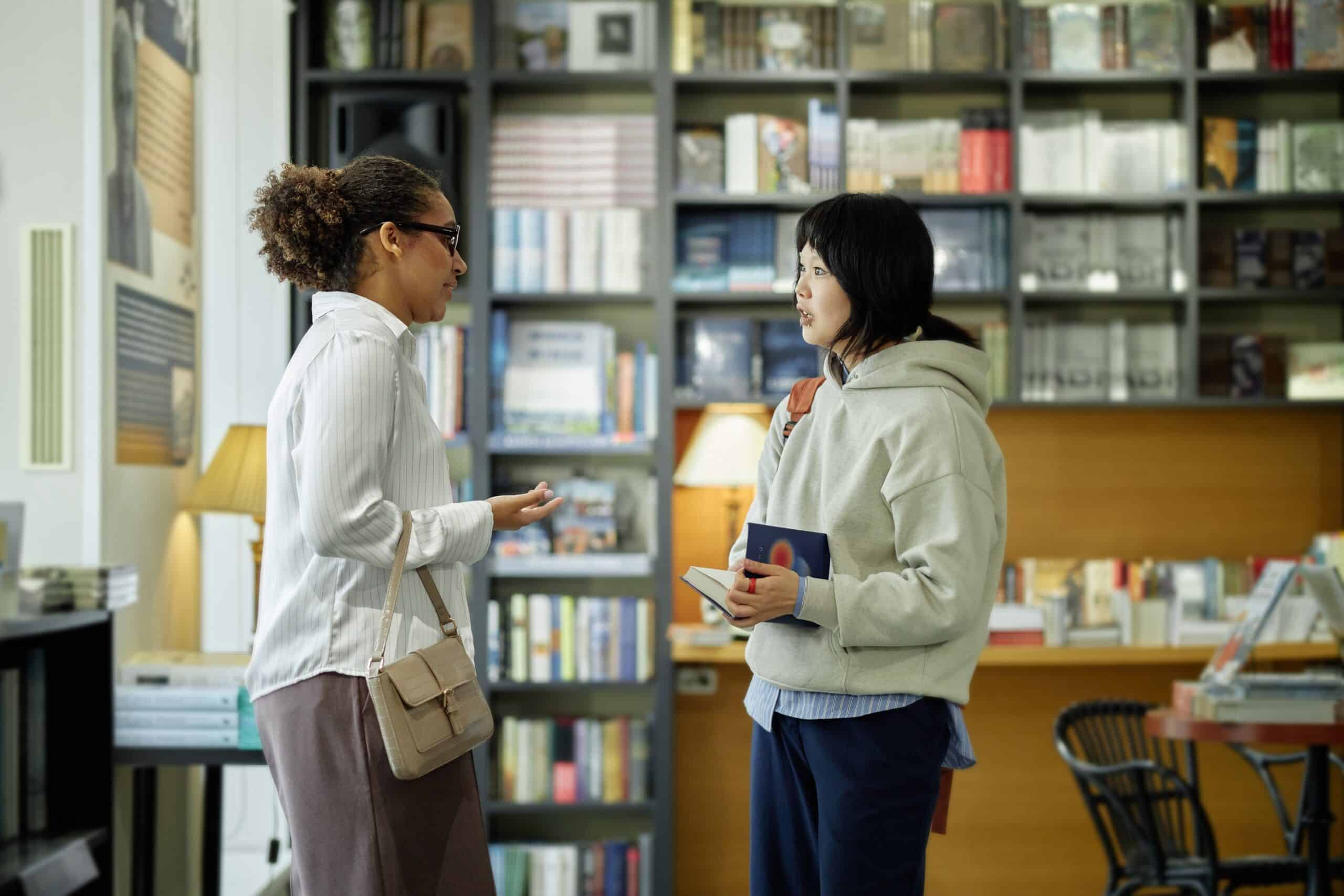 Two women having a supportive professional conversation in a library